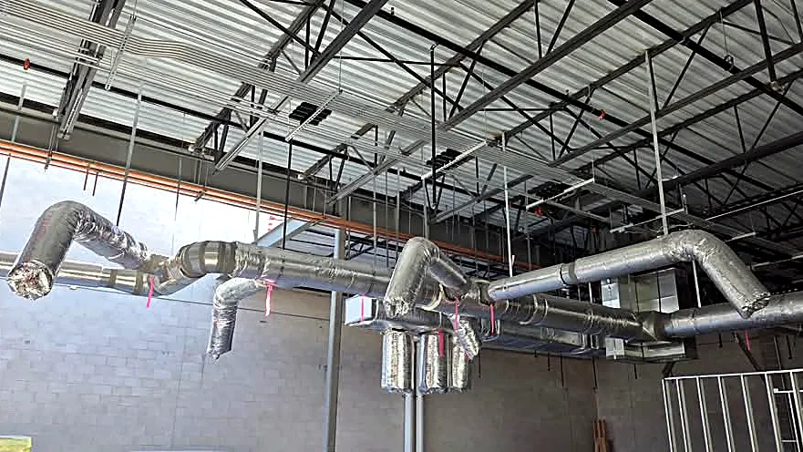 Insulated duct runs across an open commercial ceiling