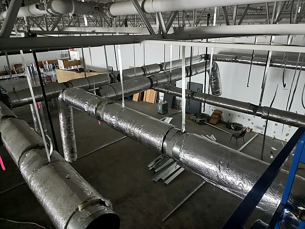 Insulated round duct and branch runs under a steel roof deck